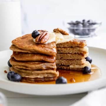 Vegan Whole Wheat Pancakes with syrup and a slice cut out.