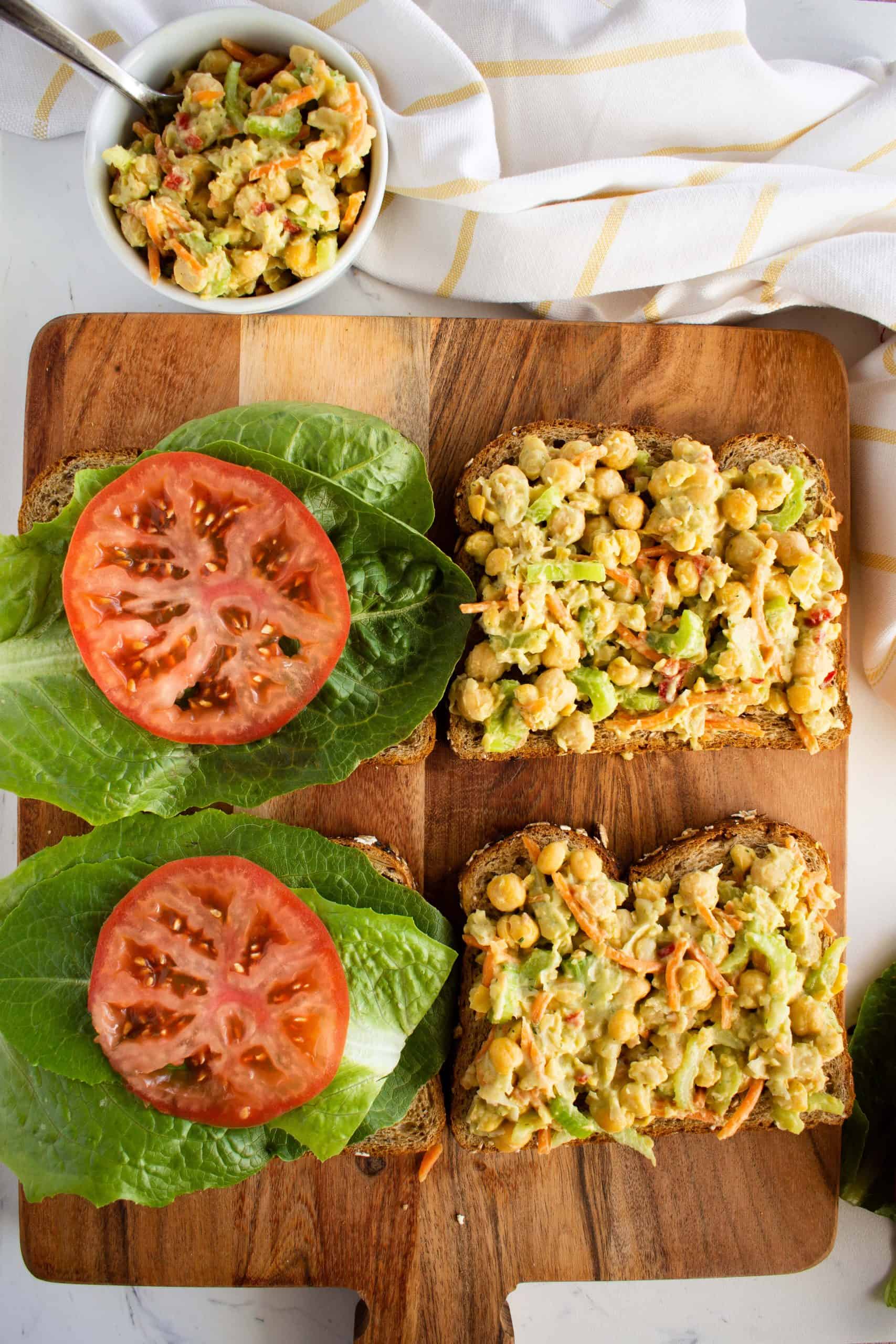 slices of bread with lettuce, tomatoes and chickpea filling.