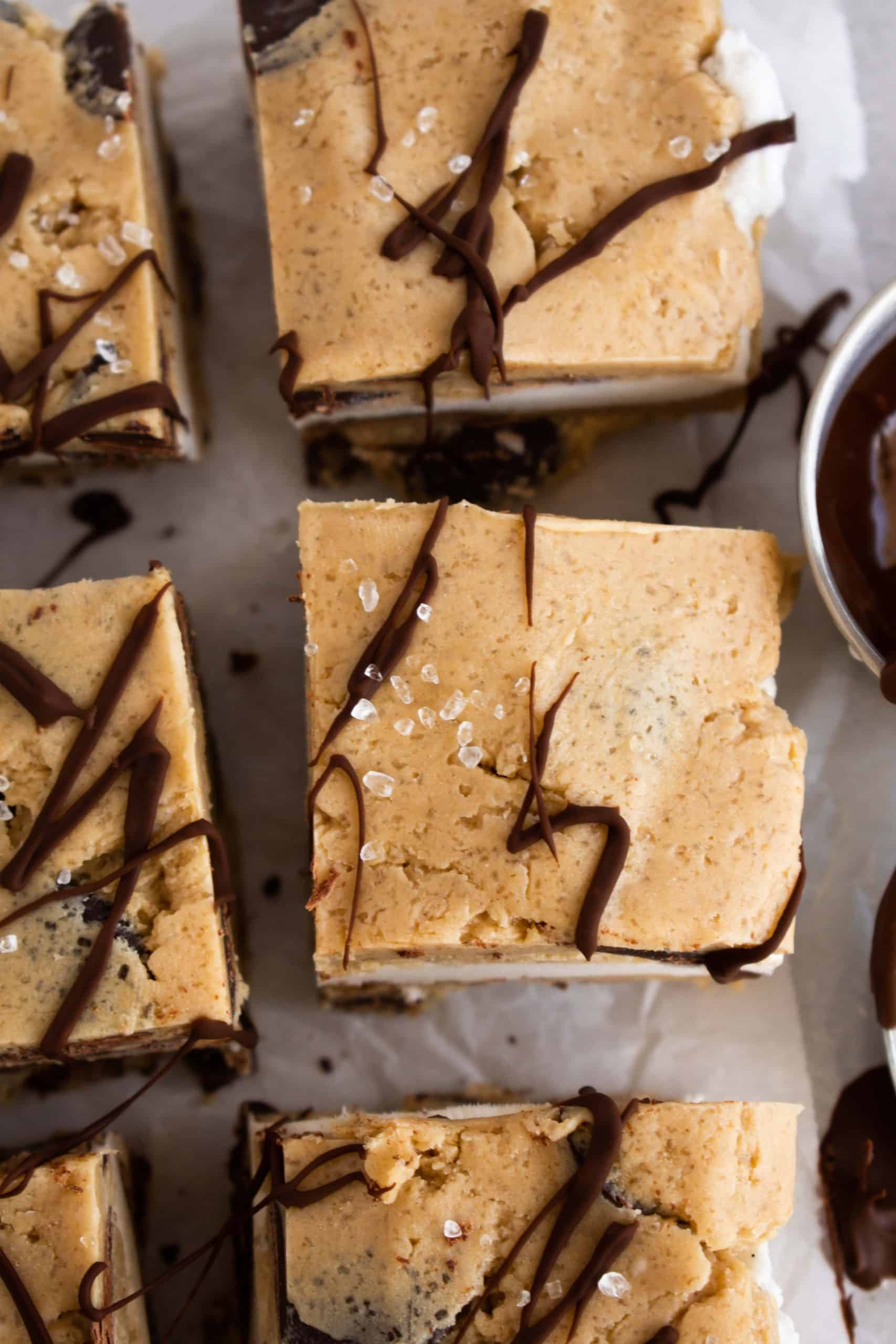 Cookie dough ice cream sandwiches on a tray with chocolate drizzle.