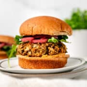 chickpea falafel burger on a whole wheat bun with hummus, arugula and pickled red onions
