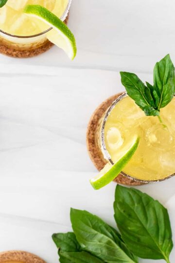 cucumber basil margarita garnished with a lead of basil and lime.