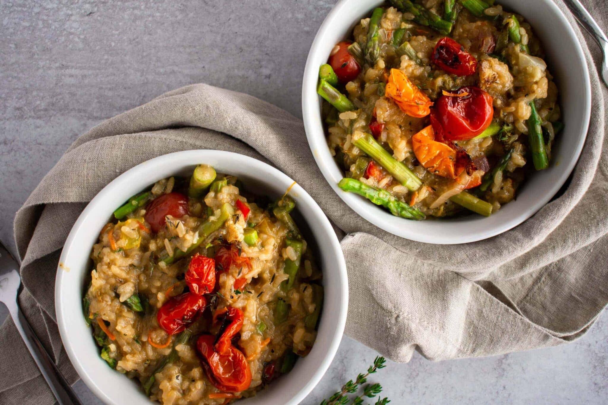 summer risotto packed with colorful veg in white bowls.