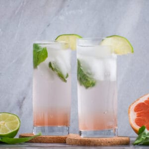 grapefruit vodka soda in a collins glass with lime and basil garnishes