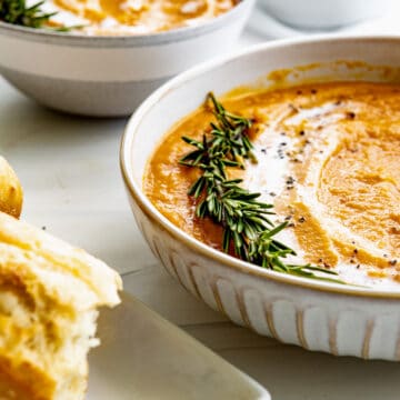 butternut squash bisque with a sprig of rosemary and gentle coconut milk swirls.