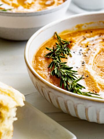 butternut squash bisque with a sprig of rosemary and gentle coconut milk swirls