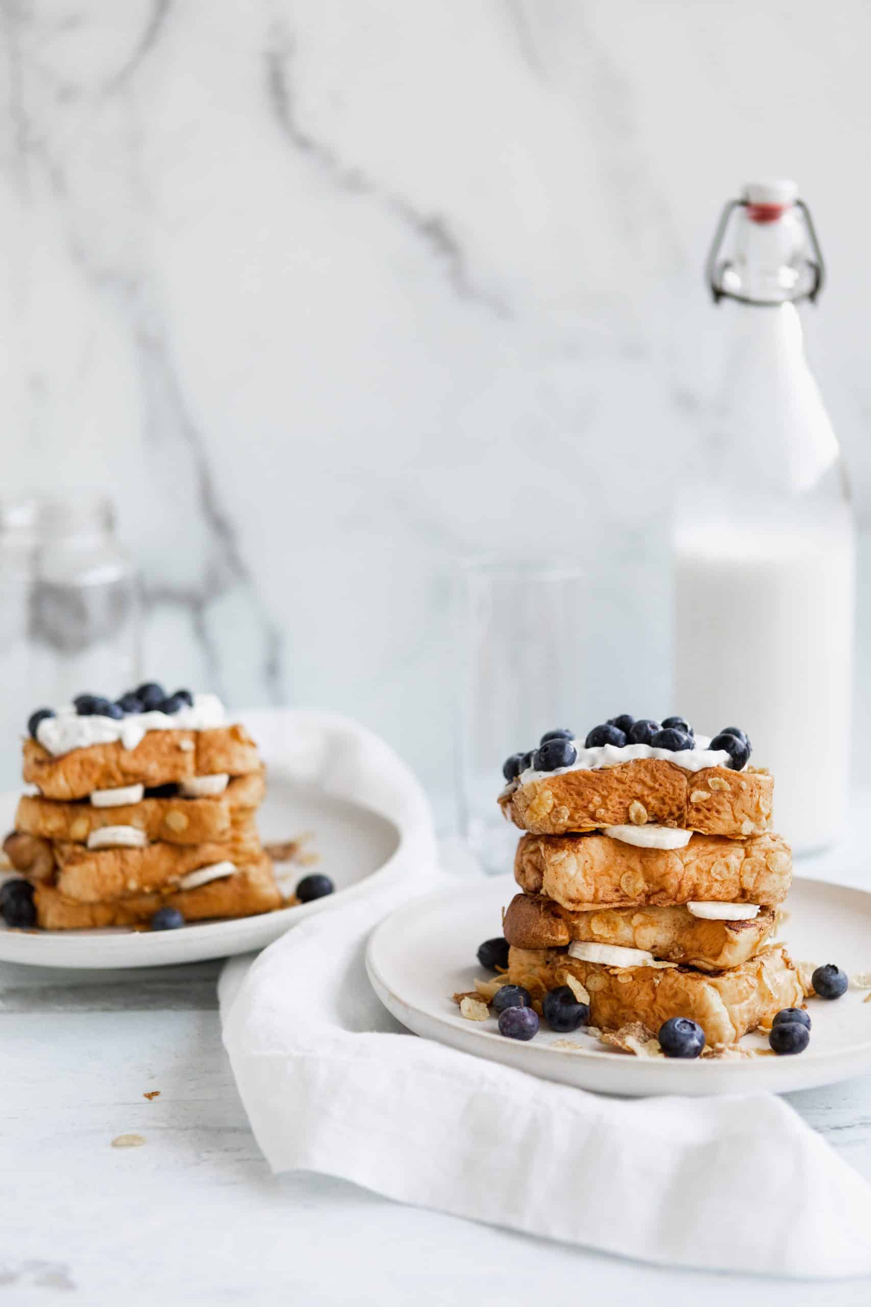 bricohe french toast with blueberries and a bottle of milk in the background.