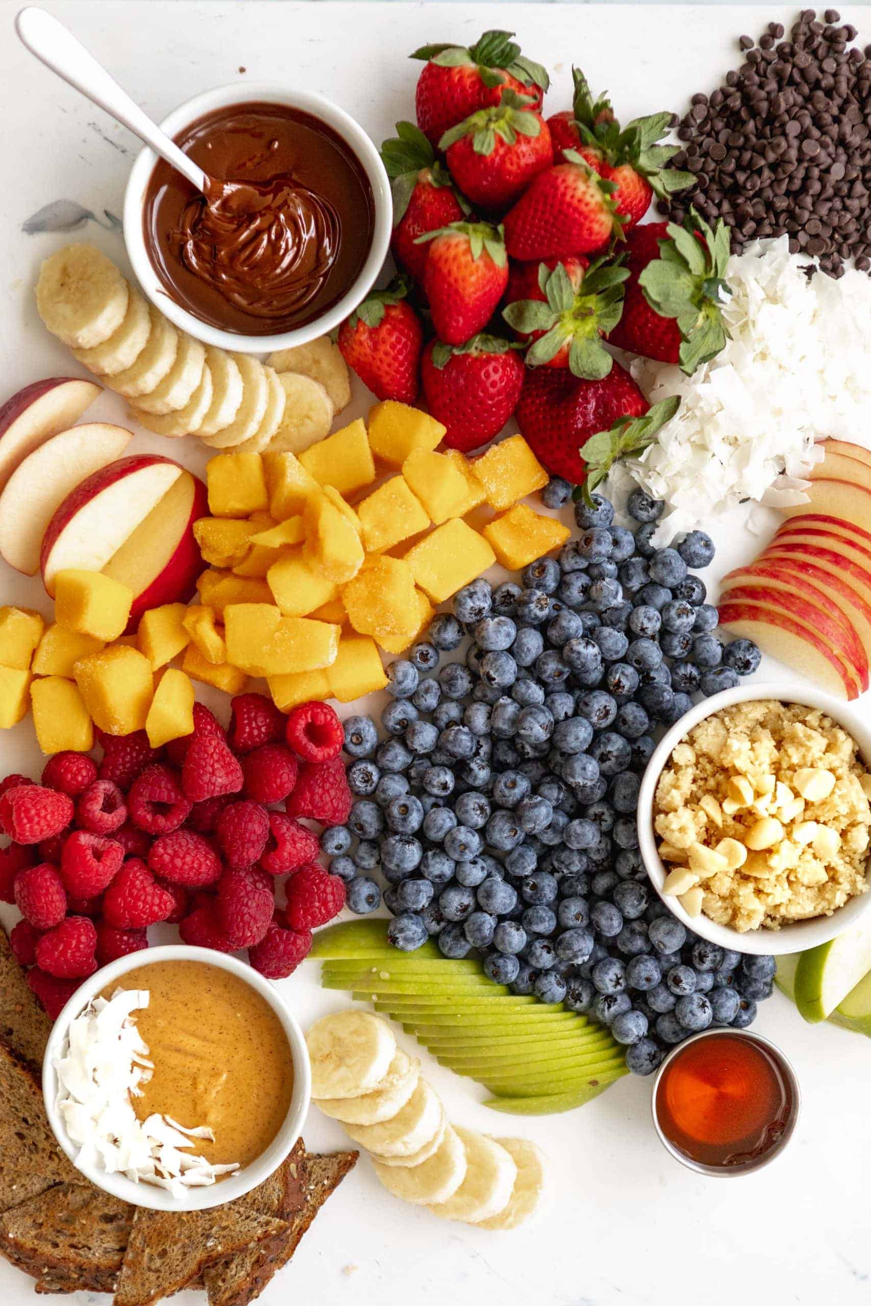 Mac nut butter board with chocolate, peanut butter, fruit, and coconut flakes.