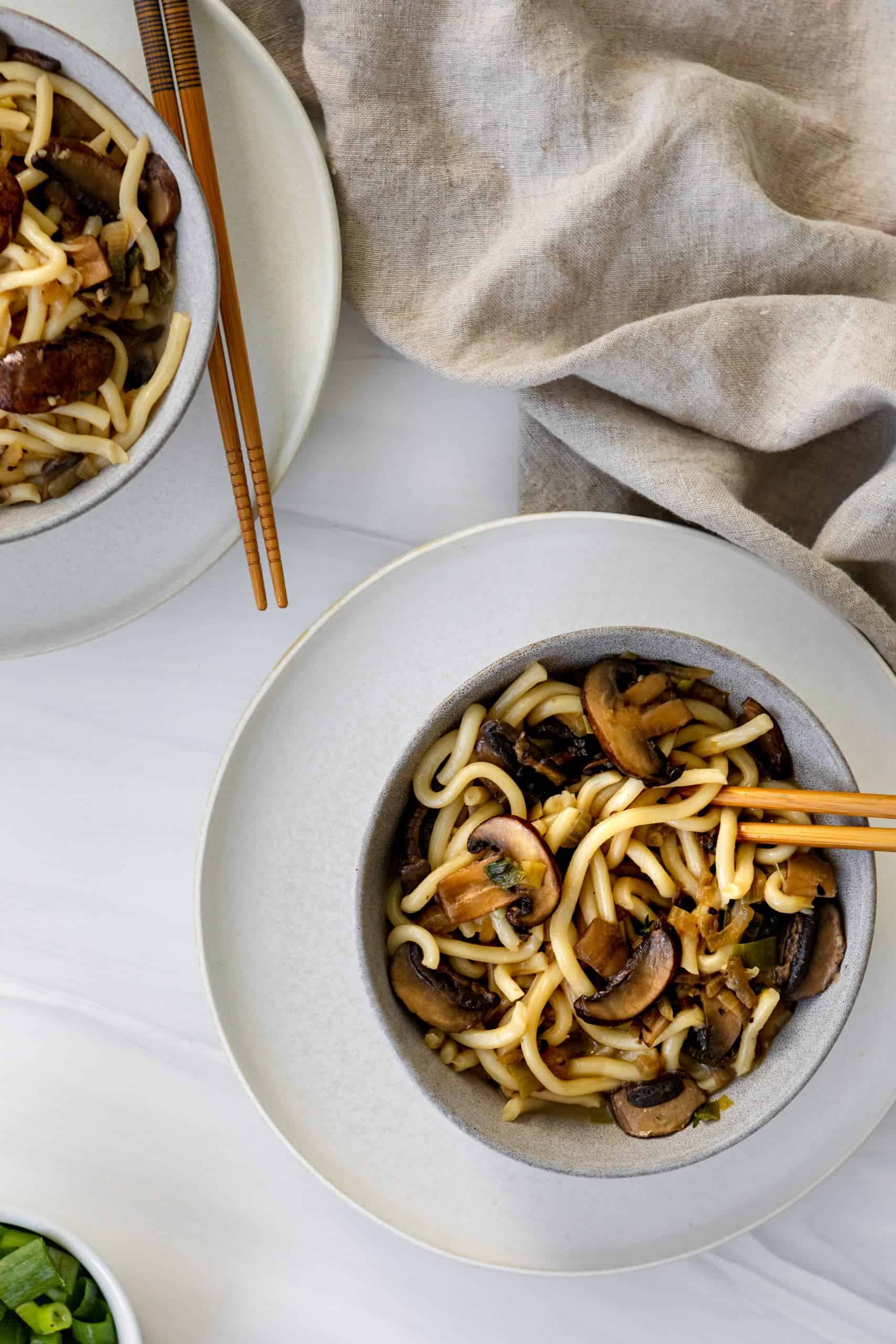 Mushrooms and udon noodles in a bowl with chopsticks