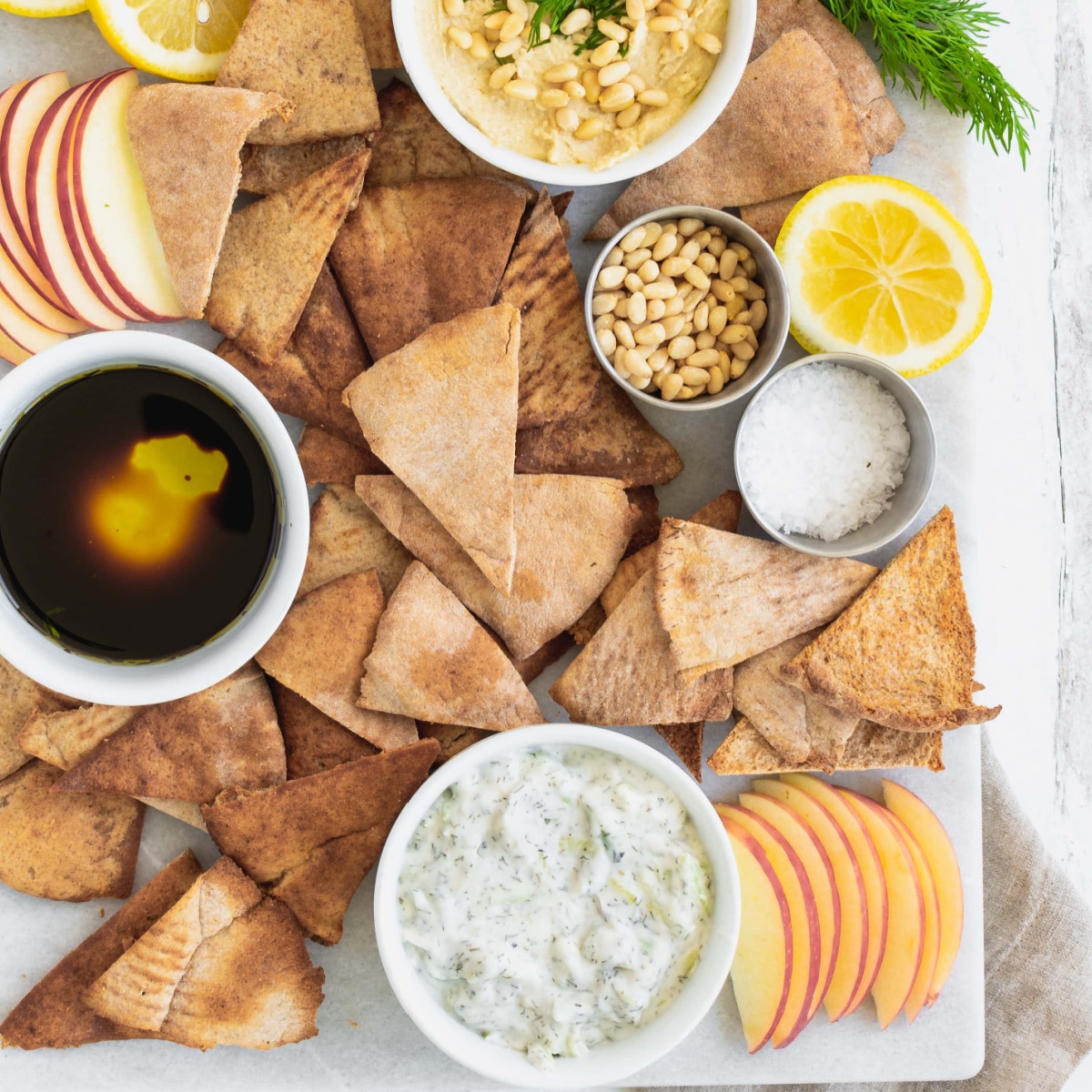 Vegan Charcuterie Board Vegan Appetizer with vegan pita chips, hummus and lemon wedges.