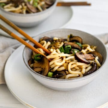 mushroom udon noodles in a bowl with chopsticks.