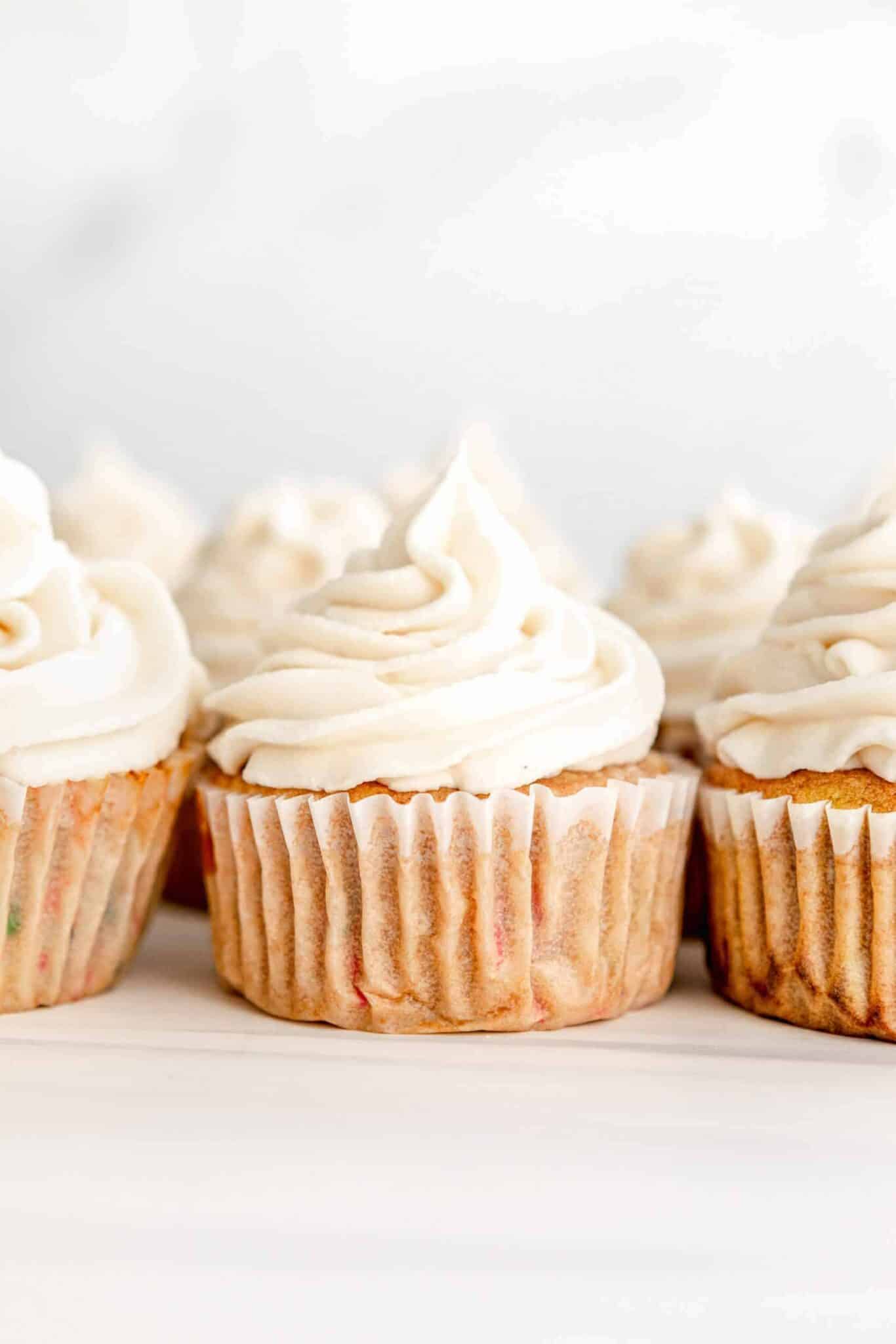 Vegan funfetti cupcakes in a row with vegan vanilla buttercream frosting.