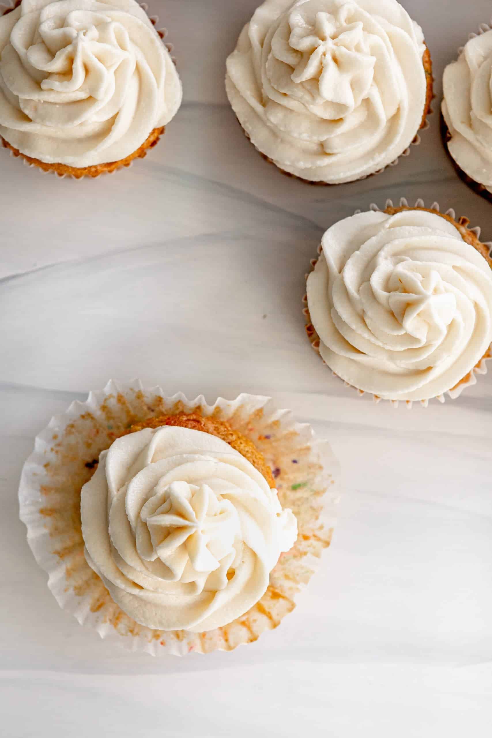 Vegan funfetti cupcakes with vegan vanilla buttercream frosting on a cupcake wrapper.