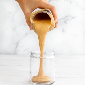 peanut butter sauce pouring into a jar in a long thick stream.