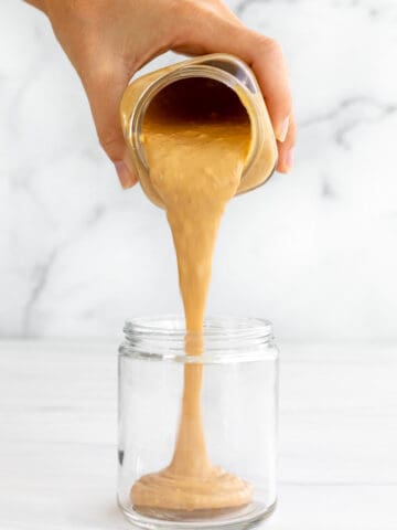 peanut butter sauce pouring into a jar in a long thick stream
