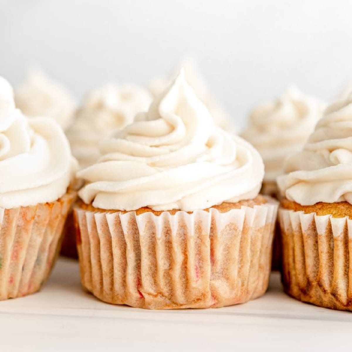 Vegan funfetti cupcakes in a row with vegan vanilla buttercream frosting.