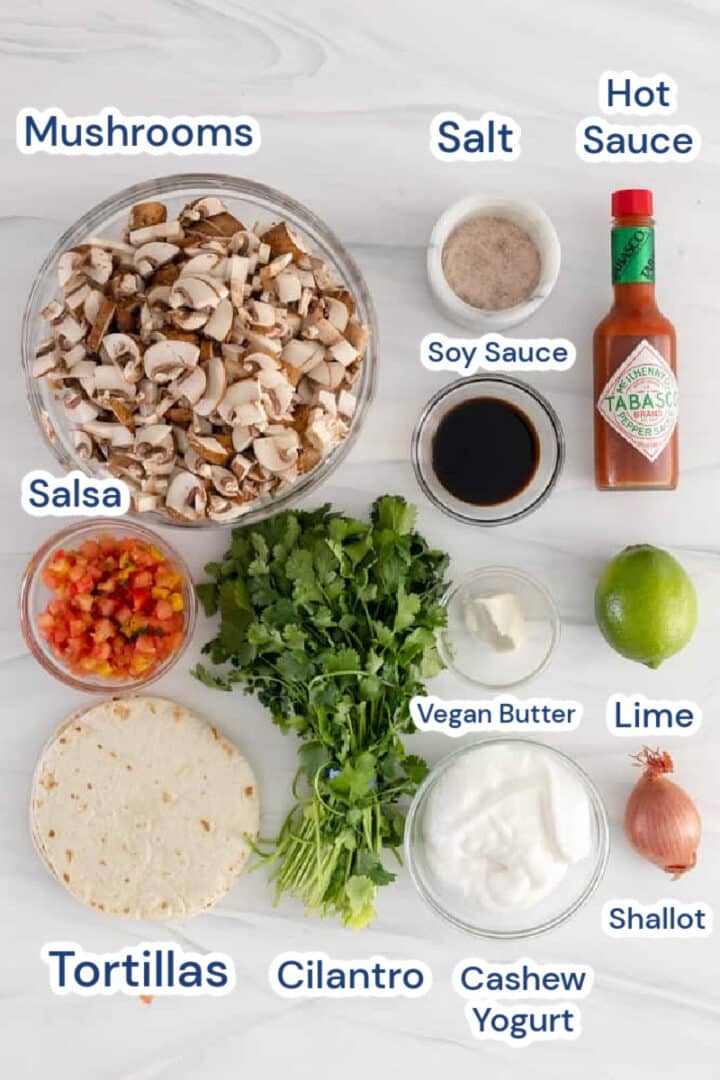 Ingredients for vegan mushroom tacos - mushrooms, sweet salsa, tortillas, cilantro, salt, soy sauce, vegan butter, cashew yogurt, hot sauce, lime, shallot.