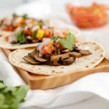 Vegan Mushroom Tacos on a plate with salsa and mushroom toppings around.