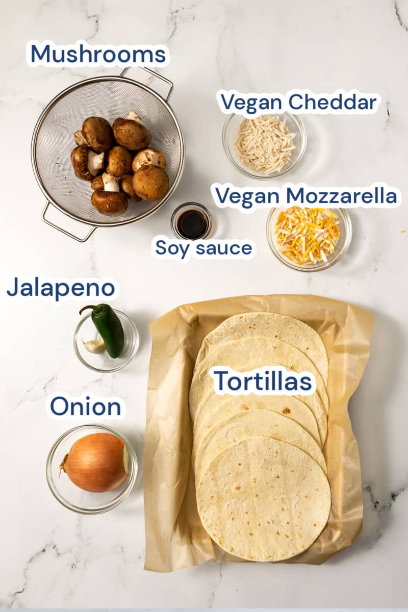 ingredients of vegan mushroom quesadilla, mushrooms, vegan mozzarella. soy sauce, jalapeno, onion, tortillas, vegan cheddar.