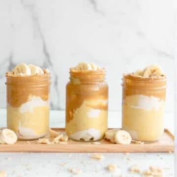 vegan peanut butter pudding in a glass mason jar. sliced banana and cream on the top of the pudding.