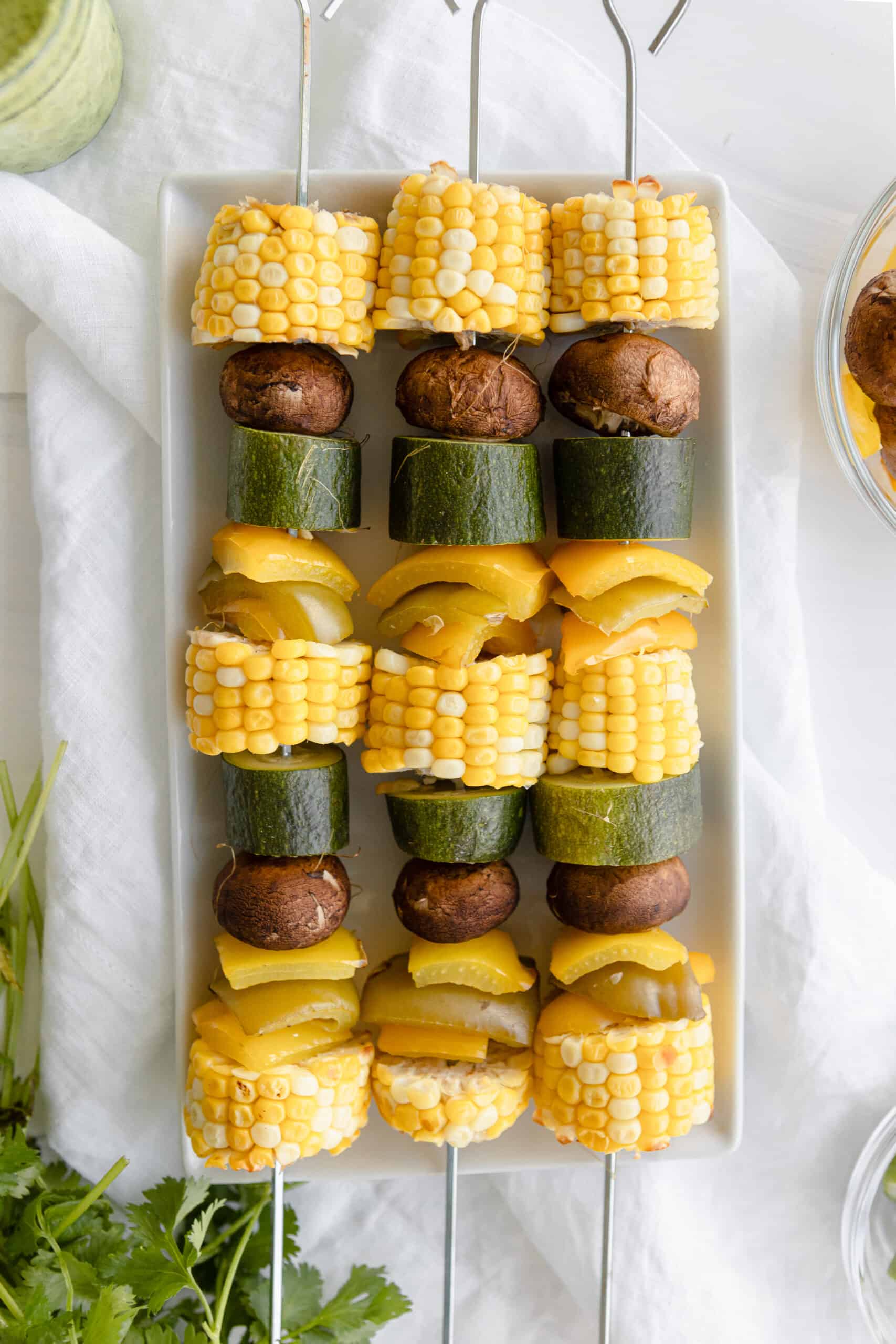 Grilled Veggie Kebabs overhead - corn, zucchini, mushrooms, and bell peppers on a metal skewer.