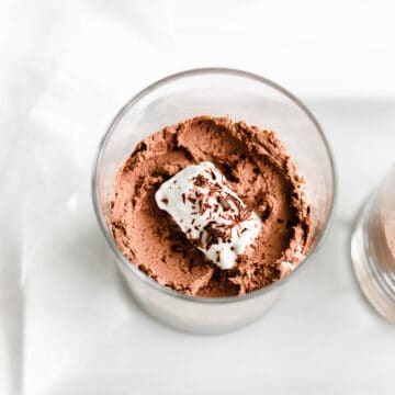 chocolate mousse in a glass with a scoop of coconut cream and chocolate shavings.