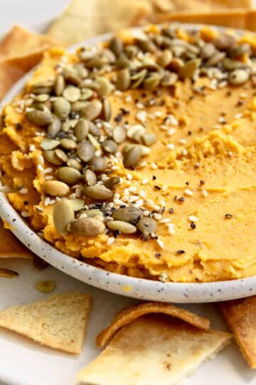 butternut squash hummus with pita chips, pumpkin seeds and sesame seeds.