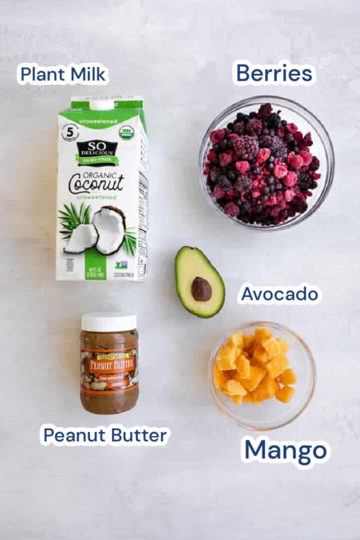 ingredients for thick berry smoothie. coconut milk, berries, peanut butter, mango and avocado.