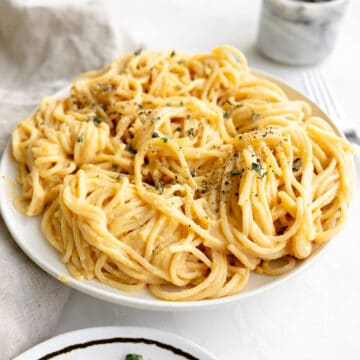 Butternut squash alfredo sauce on bucatini pasta with fresh thyme and black pepper.