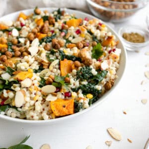 fall pearl couscous salad with butternut squash in a bowl with slivered almonds and pomegranate seeds.