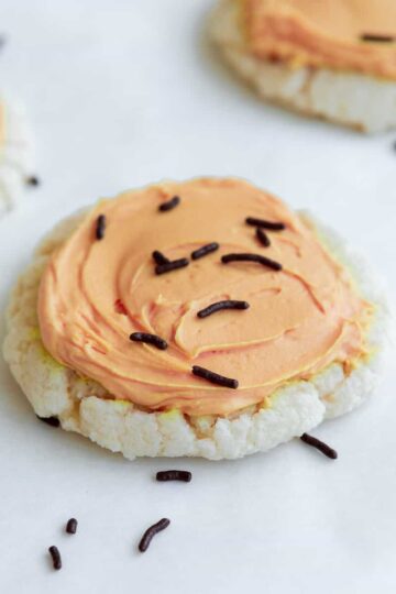 soft vegan sugar cookie with pale orange frosting and chocolate sprinkles.