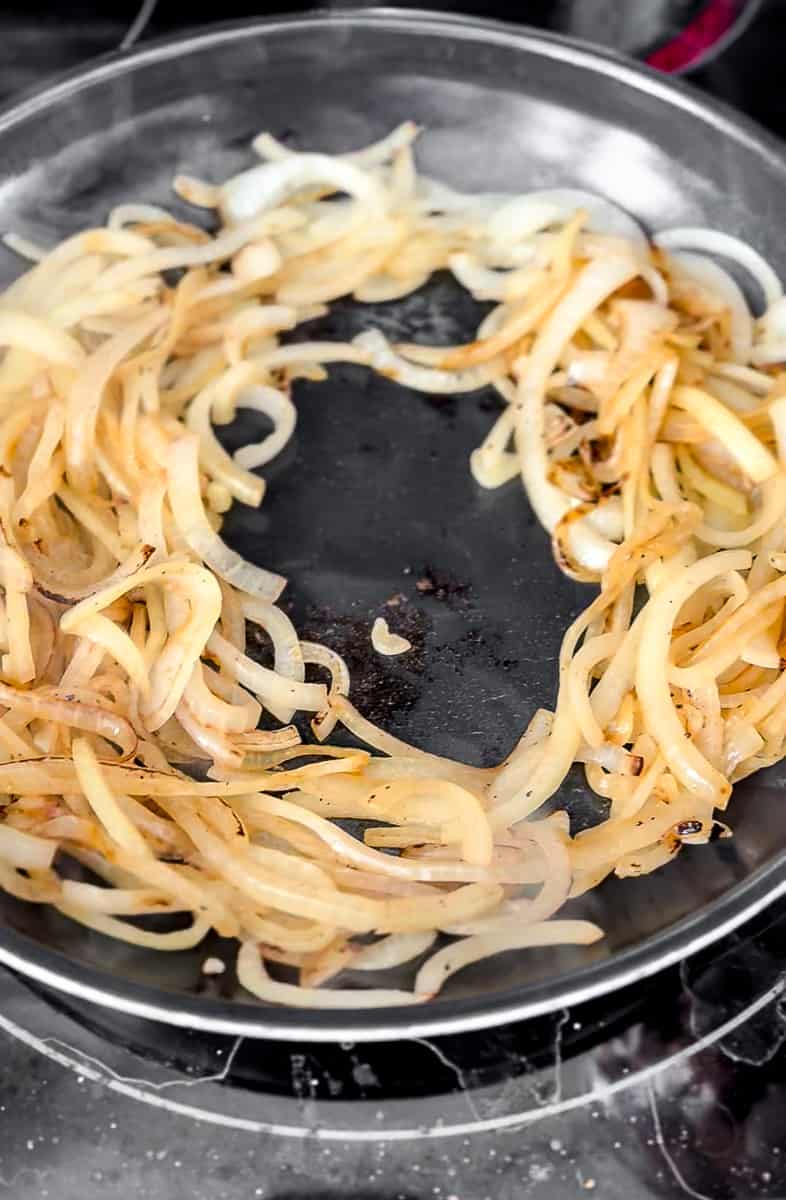 Slightly brown and translucent onions in a frying pan
