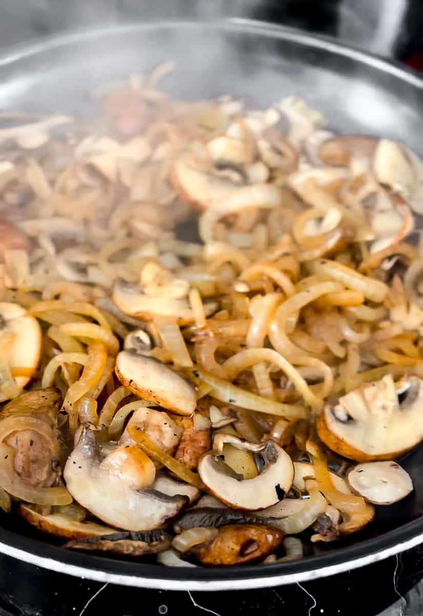 Browned onions and sauteed mushrooms in a frying pan