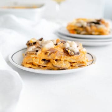 layers of vegan butternut squash lasagna topped with mushrooms and vegan mozzarella