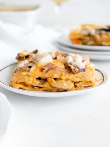 layers of vegan butternut squash lasagna topped with mushrooms and vegan mozzarella