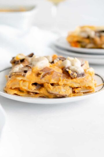 layers of vegan butternut squash lasagna topped with mushrooms and vegan mozzarella.