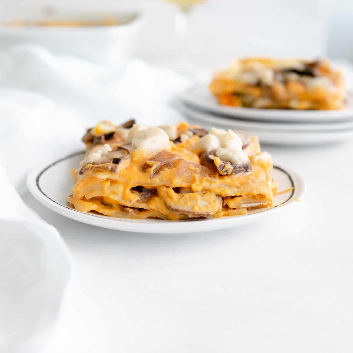 layers of vegan butternut squash lasagna topped with mushrooms and vegan mozzarella.