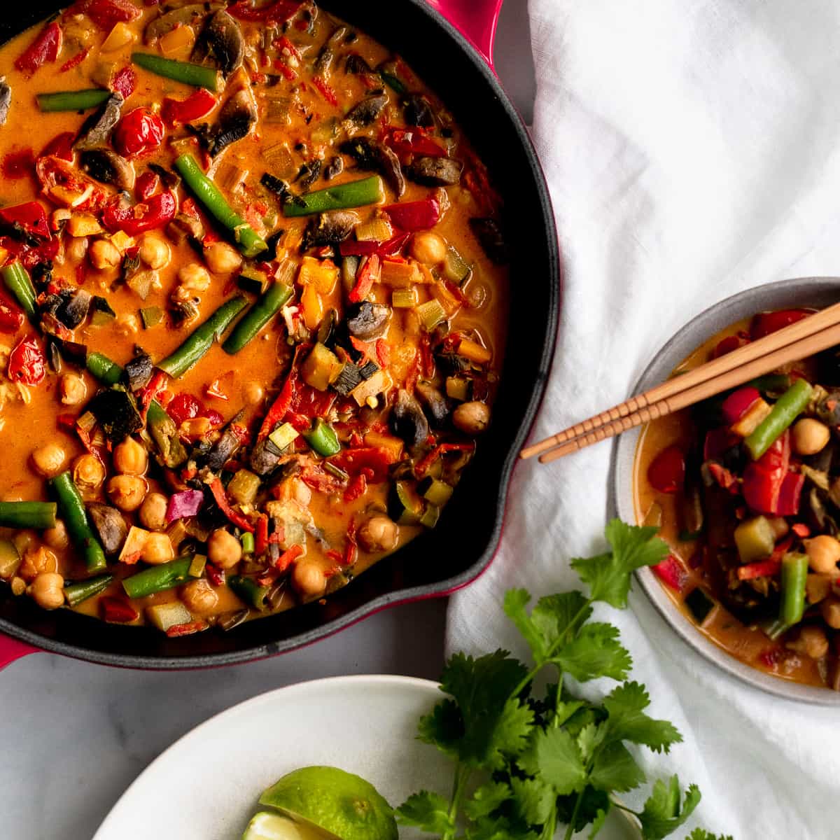 chickpea curry in a skillet with a bowl and chop sticks.