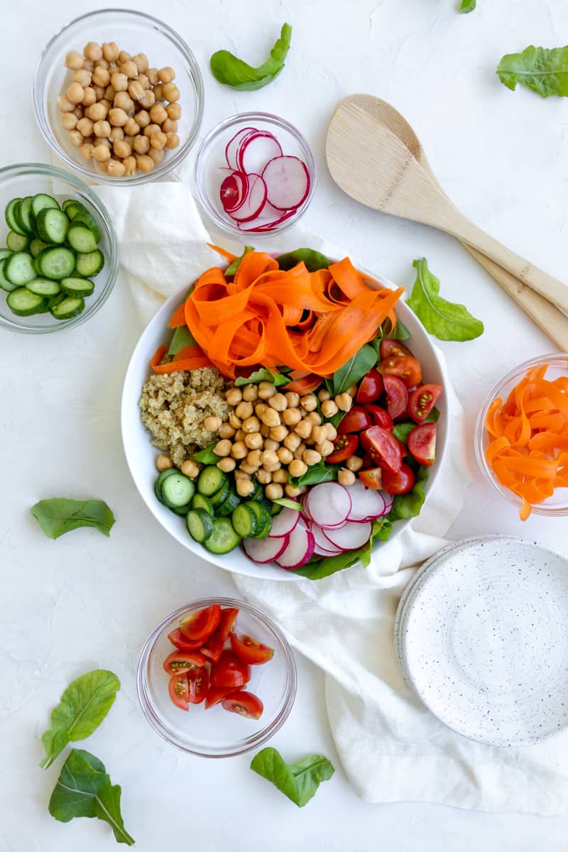 salad with rainbow colors - carrot ribbons, quinoa, chickpeas, sliced cucumbers and radishes, tomatoes and greens