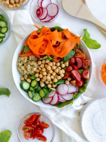 salad with rainbow colors - carrots, quinoa, chickpeas, cucumbers, greens, radishes, and tomatoes