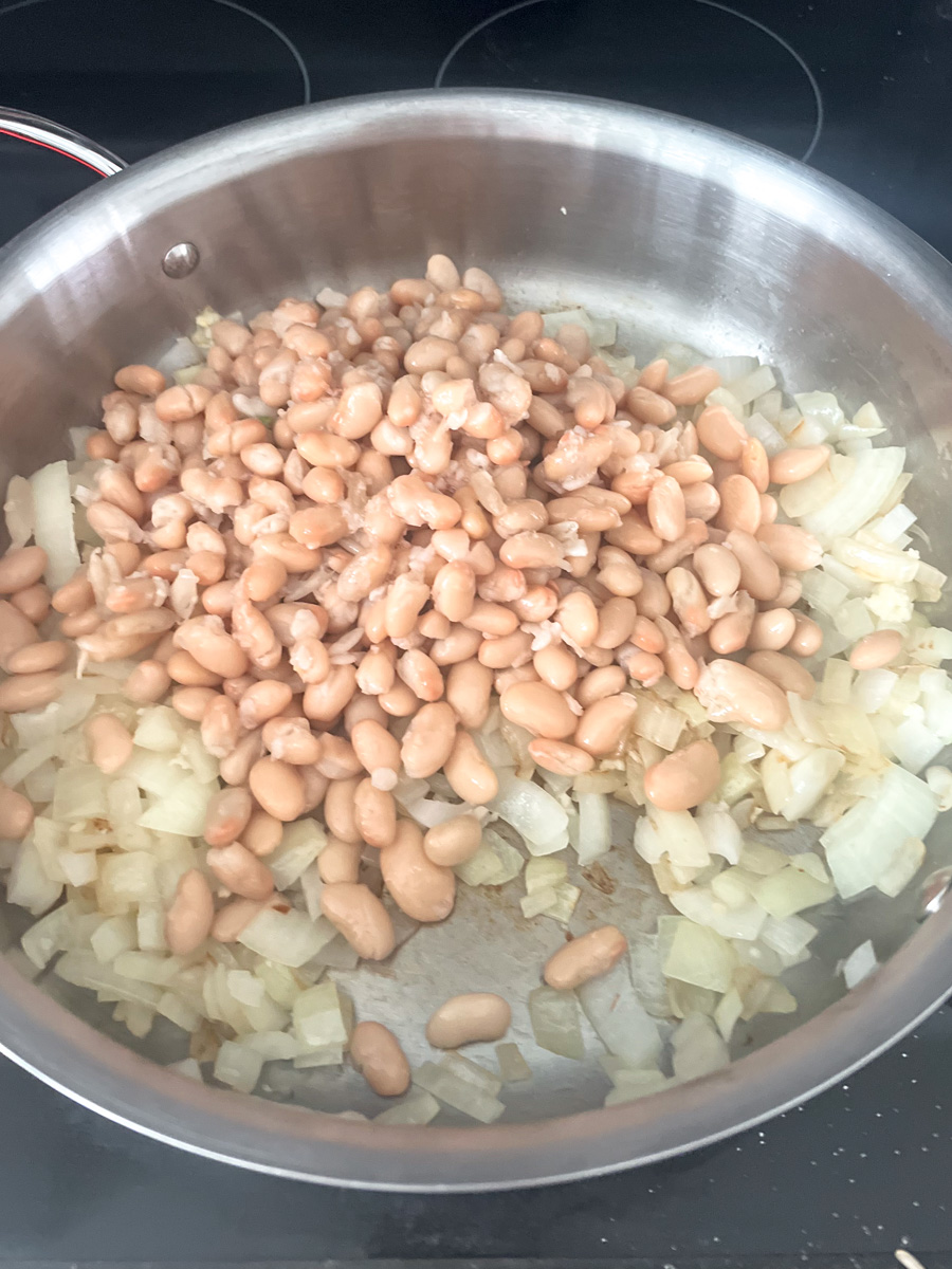 sauteed onions and white beans in a pan