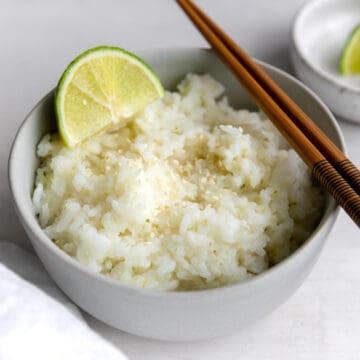 coconut sticky rice garnished with a lime and sesame seeds