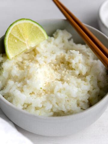 coconut sticky rice garnished with a lime and sesame seeds