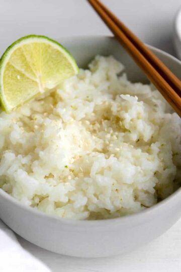 coconut sticky rice garnished with a lime and sesame seeds.