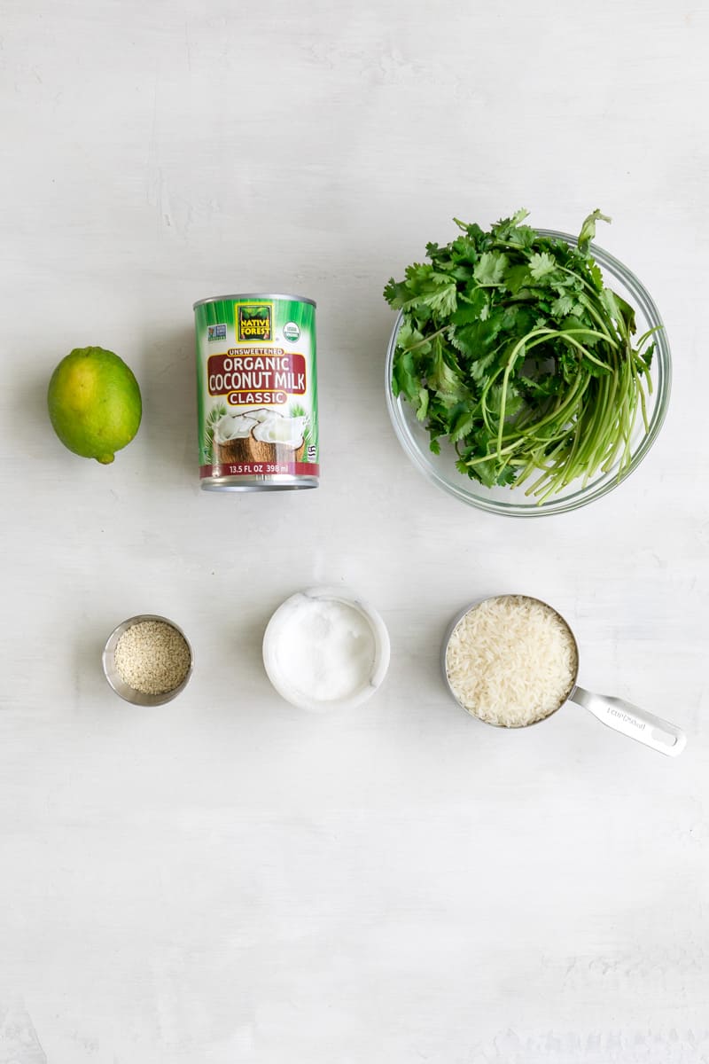 Coconut lime rice ingredients: lime, coconut milk, cilantro, sesame seeds, salt and white rice.