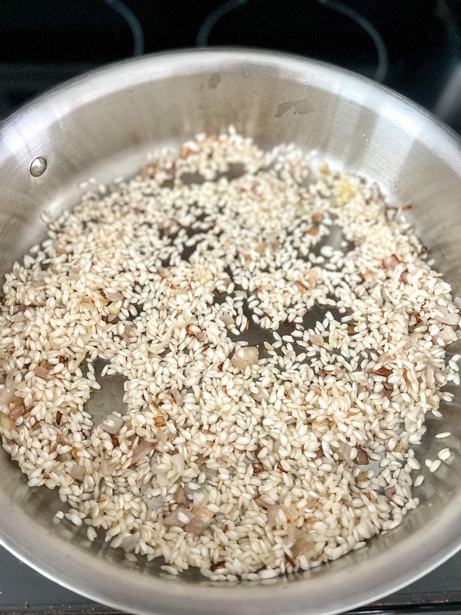 toasting arborio rice in a large flat bottomed pan with sauteed shallots