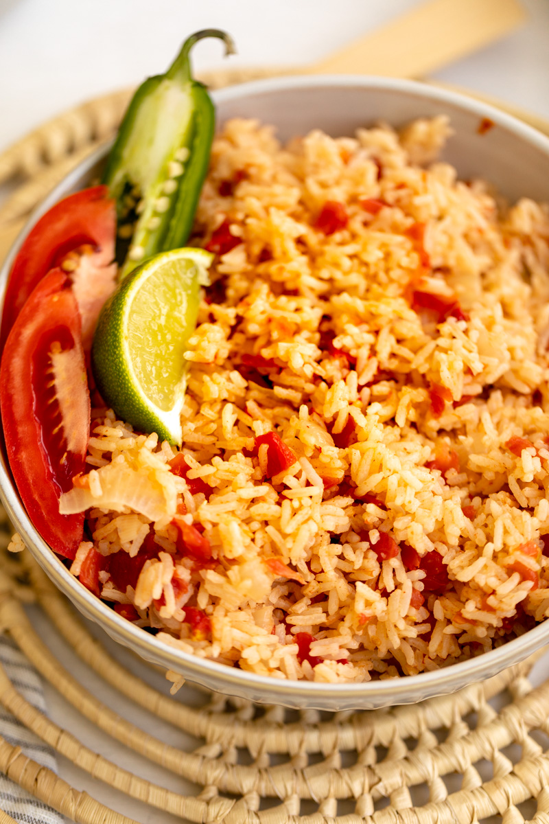 mexican red rice in a bowl with fresh tomato, lime and jalapeno 