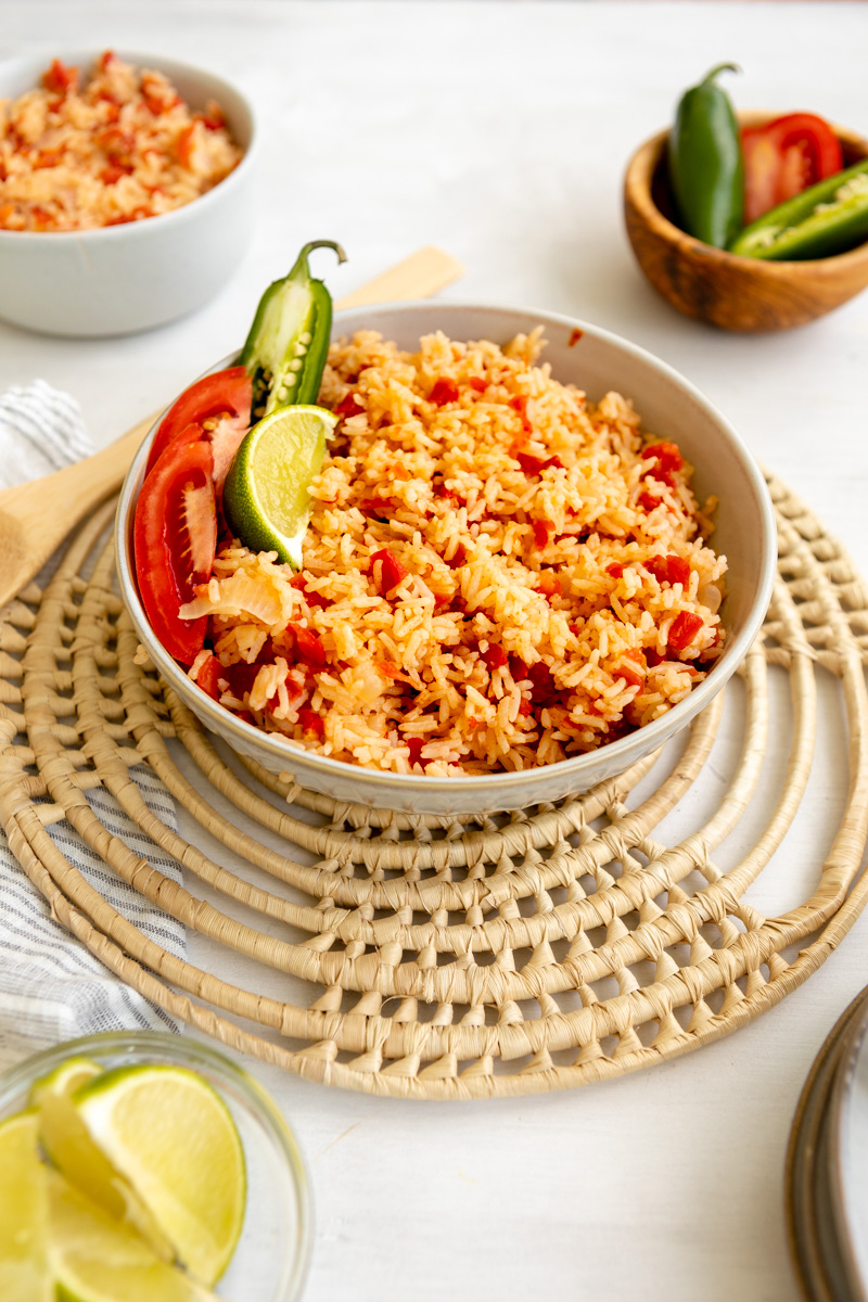 mexican red rice in a bowl garnished with tomatoes, lime and jalapeno 