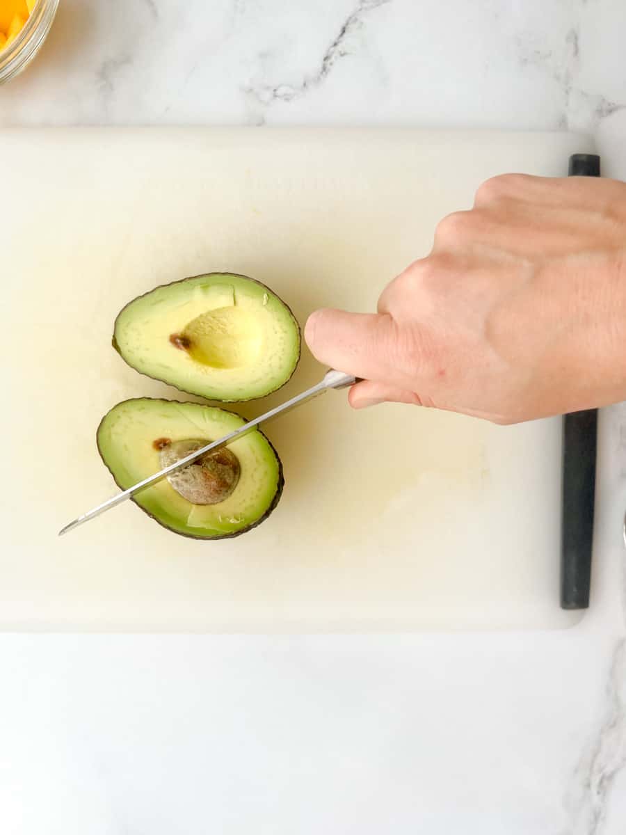 halved avocado with knife wedged into pit