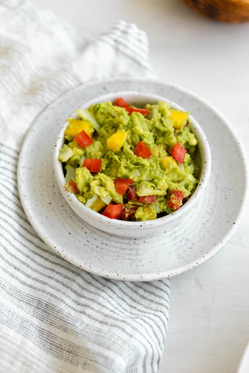 guacamole in a bowl with tomatoes and mango