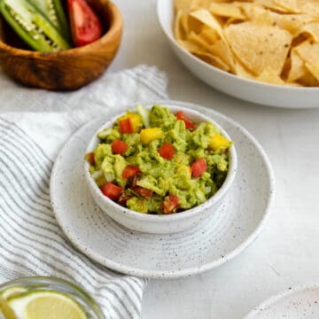 mango guacamole in a bowl with tomatoes.